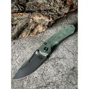 The Spaceman Knives N1 EDC, a folding knife with a textured green Micarta handle, is displayed open on a stone surface with rugged tree bark in the background.