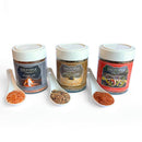 The SALTOPIA Infused Sea Salts FOODIE AFICIONADO Gift Set features three jars—Hickory Salt, Sweetening Agent, and Fiesta Seasoning—with white ceramic spoons. Fiesta Seasoning’s vibrant Mexican flavors pop against a crisp white background.
