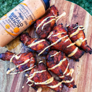 A pile of grilled chicken wings drizzled with creamy ranch buffalo sauce on a wooden board, with a bottle of Terrapin Ridge Farms Buffalo Ranch Squeeze at the top left.