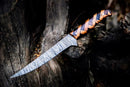 The Texan Knives Custom Handmade Damascus Steel Fillet Knife for Sale (13" length) features a patterned blade and a tiger-striped spiral wooden handle, displayed atop a weathered dark tree trunk.