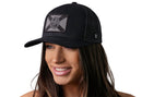 A smiling woman with long brown hair wears the Haka Hat Florida Flag Trucker Hat, a black tactical snapback with a circular seal patch, against a white background.