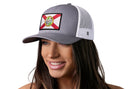 A woman wearing a Haka Hat Florida Flag Trucker Hat | Black FL Snapback with a mesh back and state flag patch smiles, looking slightly to the side.