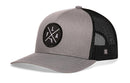 The Haka Hat Florida Trucker Hat is a gray and black snapback with a mesh back and features a round black patch on the front with white F, L, and A letters separated by crossed lines.