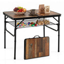 A Folding Camping Table with Adjustable Heights Storage Net & Handle by DirectDeals holds fruit, a mug, and snacks on top, colorful treats on its mesh shelf below, with another table folded and leaning against it.