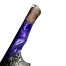 A close-up of the Spaceman Knives Gravity Series Nakiri features a wood handle with shiny purple resin and gold accents. Its AUS-10 steel blade shows a striking Damascus pattern, displayed on a solid white background.