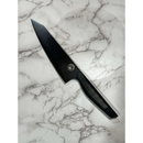 A sleek, black Dark Matter Kiritsuke by Spaceman Knives rests on a white marble surface with gray veining.