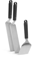 The Napoleon Griddle Starter 3-Piece Set by Napoleon Grills (GATL012) features three stainless steel spatulas with black handles—two long, rectangular blades and one short, wide blade—standing upright against a white background.