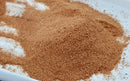 A close-up of a mound of fine, light brown World Spice Galangal Powder on a white surface, with some powder scattered around the edges—an essential Southeast Asian aromatic from World Spice, often used to add warmth and depth to Thai curries.