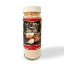 A clear glass jar of SALTOPIA Infused Sea Salts, labeled “Saltopia Garlic Salt: MOUTH FULL OF MAGIC,” features garlic bulbs on the front and a white lid, filled with light-colored sea salt for gourmet garlic seasoning.