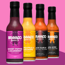 Four bottles of Bravado Spice hot sauce—including Ghost Pepper & Blueberry, Pineapple & Habanero, Black Garlic Carolina Reaper, and Aka Miso—are arranged against a purple background, highlighting some of the extra-hot sauces from Hot Ones Season 3.