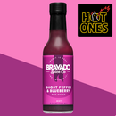 A bottle of Bravado Spice Ghost Pepper & Blueberry Hot Sauce - Hot Ones Season 3, an extra-hot sauce from Bravado Spice featured on Season 3 of Hot Ones, stands on a pink background. The Hot Ones logo appears in the top right corner.