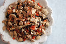 A close-up of a bowl filled with World Spice Ginger Sunrise by World Spice—an artful blend of dried, chopped herbs and roots in varied shades of brown, orange, and beige—perfect for brewing a soothing cup of lemon and ginger tea, presented on a light surface.