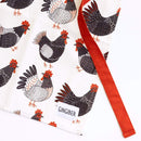 The Gingiber Chicken Apron by Gingiber is a white cotton kitchen apron with illustrated black and white chickens with red combs and feet, an orange strap, a bottom-corner label, and an adjustable fit for comfort while cooking.
