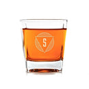 A square-based Whiskey Glasses: Modern by Swanky Badger filled with amber liquid, etched with a triangular logo containing the letter S.