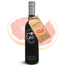 A dark glass bottle of Georgetown Olive Oil Co. Grapefruit White Balsamic from Georgetown Olive Oil Co., with a tag, is placed in front of a sliced pink grapefruit.
