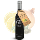A bottle of Georgetown Olive Oil Co. Greek Seasoning White Balsamic by Georgetown Olive Oil Co., featuring a brown tag, is displayed in front of illustrations of a lemon slice, onion, herbs, and oregano.