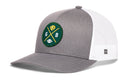 The Haka Hat Green Bay Trucker Hat is a gray and white snapback featuring a green circular patch with yellow and white icons—a cheese wedge, football, crossed “G” and “B”, and two yellow bats—true to the Haka signature style.