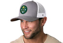 Man wearing a Haka Hat Green Bay Trucker Hat | Gray-White GB Cheese X Football Snapback by Haka Hat, featuring a green circular patch with crossed yellow lines, a football, and a cheese wedge.