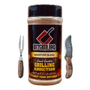 A container of Butcher BBQ Grilling Addiction BBQ Rub Seasoning sits between a wooden-handled meat fork on the left and a textured chef’s knife with a wooden handle on the right.