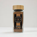A 75g glass jar of Spice Wheel Ground Nutmeg by Spice Wheel, featuring a bamboo lid, is displayed on a white surface with a plain background. This aromatic spice delivers warm, subtly sweet notes that are ideal for enriching both sweet and savory recipes.