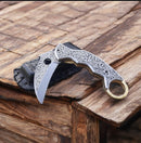 The Texan Knives Hand-Engraved J2 Steel Folding Knife with Leather Case (7.5" overall) features intricate handle designs—an eye-catching piece from Texan Knives, perfect for elevating your everyday carry collection.