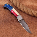 The Texan Knives Exclusive Texas Flag Damascus Steel Pocket Knife features a 3" patterned blade and a blue, red, and cream handle—complete with leather sheath, it’s the perfect gift for collectors and a standout piece for any premium knife collection.
