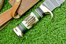 A close-up shows the Texan Knives Deluxe Dundee Knife—16" handmade Damascus steel blade, brass guard, and black, green, and ivory stag horn handle—resting on artificial grass beside its custom leather sheath.