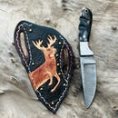 The Texan Knives Custom Handmade Damascus Steel Bull Cutter Knife with a patterned blade and dark marbled handle rests beside its sheath, both displayed on textured wood.