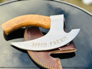 The Texan Knives Vikings Pizza Cutter features a custom handmade 8-inch J2 steel blade with a wooden handle and runic engravings, resting on a brown leather sheath atop a glossy black surface.