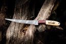 The Texan Knives Custom Handmade Filleting Knife for Fish features a 13" Damascus steel blade and a camel bone & rosewood handle, displayed on a weathered tree stump.