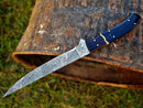 A Texan Knives Custom Handmade Damascus Fillet Knife, 13-inch with a Buffalo Horn & Rosewood handle, lies on weathered, rusted metal outdoors.