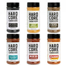 The Hardcore Carnivore BBQ Rub Sampler Set by Hardcore Carnivore includes six seasoning bottles—Black, Amplify, Camo, Tex-Mex, Red, and Sweet BBQ—each with a unique colored label and bold black or red lettering.