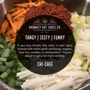 A bowl topped with green onions, carrots, cabbage, and a scoop of Korean chili paste sits beside a label for Harmacy Hot Sauce Co. Chi-Chee Kimchi Sauce 9oz—a tangy, zesty kimchi hot sauce with signature funky flair.