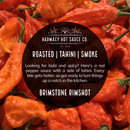 Close-up of bright red hot peppers with a circular black label overlay reading: “Harmacy Hot Sauce Co. Brimstone Inferno Extra Hot Tahini & Roasted Red Pepper Sauce 9oz”—a bold, smoky Mediterranean hot sauce.
