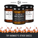 Three jars of Harmacy Hot Sauce Co., including Brimstone Inferno Extra Hot Tahini & Roasted Red Pepper Sauce, are displayed above flames. Text: "Try Harmacy's Other Sauces" and "Created in Tennessee" with a Tennessee emblem overhead.