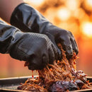 Hands in Butcher BBQ Neoprene Gloves for Pulled Pork | Heat Resistant BBQ Gloves shredding juicy pulled pork over a grill, with a blurred outdoor background and warm lighting.