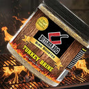 A jar of Butcher BBQ Turkey Brine & Injection positioned over a flaming charcoal grill.