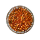 A top-down view of SALTOPIA Infused Sea Salts' HOLY MOLY Taco Seasoning shows a glass jar filled with a vibrant Mexican spice mix, featuring red, orange, and green herbs for authentic flavor.