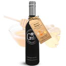 A dark glass bottle labeled Georgetown Olive Oil Co. stands before honey, a honey dipper, and fresh ginger slices—this Honey Ginger White Balsamic is expertly crafted in Modena, Italy by Georgetown Olive Oil Co., delivering the sweet and zesty taste of honey and ginger balsamic to your table.