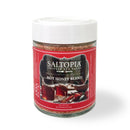 A jar of SALTOPIA Infused Sea Salts, labeled "TACO'CLOCK" from the Mexican Food Lovers Set, features a red label and white lid, revealing reddish infused sea salt inside—perfect as a seasoning for tacos and Mexican dishes.