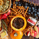 A fall-themed snack platter with apple slices, pumpkin dip with seeds, pretzel sticks, blueberries, fruit preserves, and Terrapin Ridge Farms Hot Pepper Bacon Jam (2oz), arranged around a small pumpkin on a rustic wooden surface.