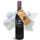A bottle of Georgetown Olive Oil Co. Huckleberry Balsamic Vinegar, crafted with aged balsamic vinegar from Modena, Italy, displays a tan tag and is set in front of several blueberries and green leaves on a white background.