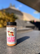 A shaker bottle of BuffalowBBQ Sassy Swine BBQ Rub featuring a cartoon bull chef on the label, sitting on a patio surface.