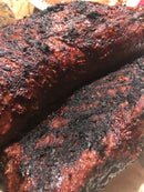 Two pieces of dark, charred barbecue meat seasoned with BuffalowBBQ Beef Bark BBQ Rub, featuring a rich rub and deep bark formation.