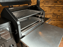 A Green Mountain Grills Ledge / Daniel Boone Pimp My Grill® Gen2 Slide-Out Rack System with two stacked, slide-out grill racks and a side shelf shown on a pellet grill with its lid open.
