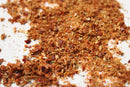 A close-up of World Spice Adjika, a vibrant salt-free seasoning by World Spice, scattered across a white surface. The blend showcases reddish, brown, and green flecks—highlighted by hints of fenugreek for added depth—capturing the essence of traditional Georgian Adjika.