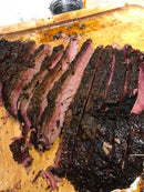 Slices of smoked beef brisket seasoned with BuffalowBBQ Beef Bark BBQ Rub, featuring a dark bark formation on a wooden cutting board.
