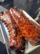 Two racks of sweet and smoky BuffalowBBQ Sassy Swine BBQ Rub glazed ribs on a metal tray.