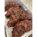Four pieces of meat coated in BuffalowBBQ Signature Blend BBQ Rub, arranged in a disposable aluminum tray.