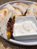 A plate of gluten-free tortilla quesadillas filled with meat and cheese, seasoned with BuffalowBBQ Bacon Ranch BBQ Rub and served with a side of sour cream.